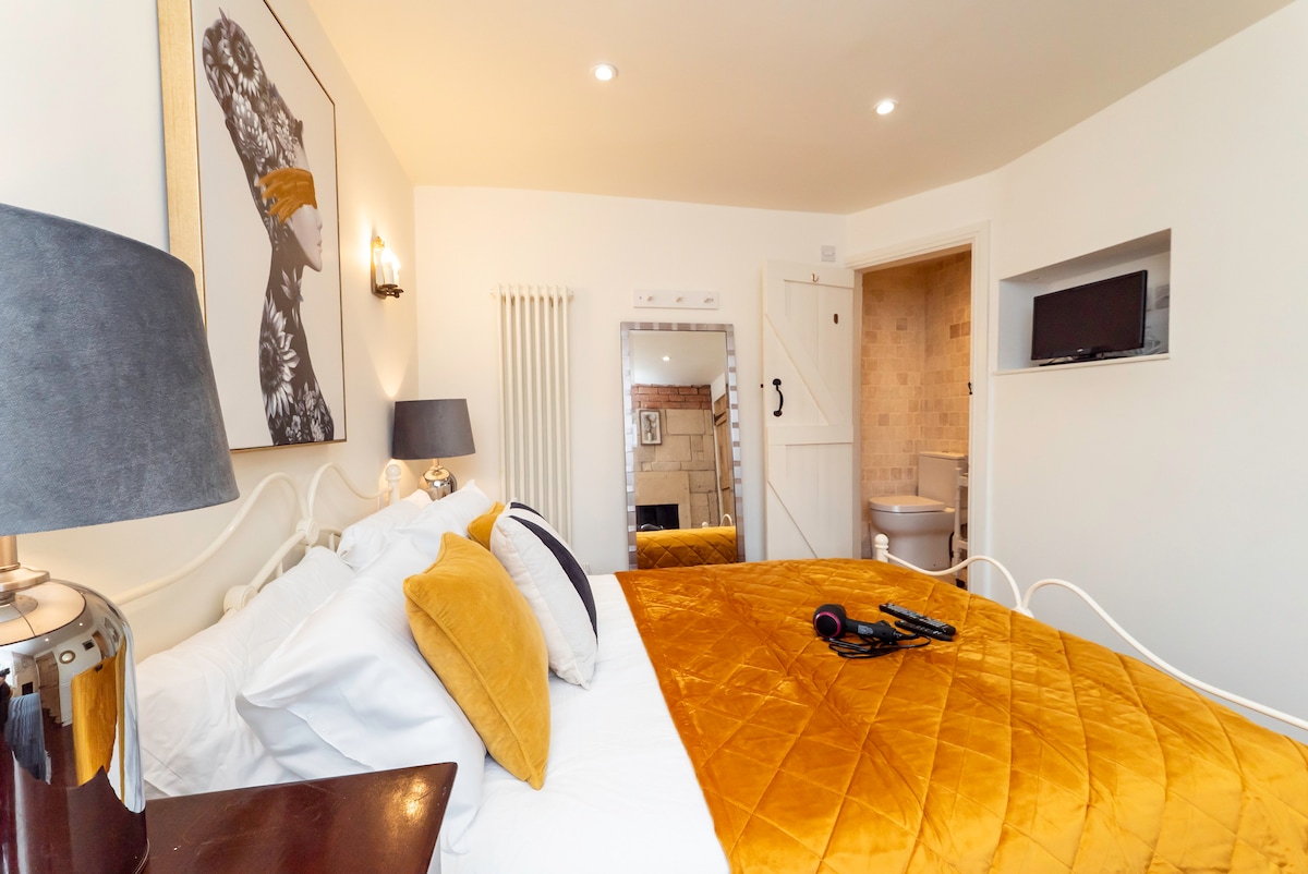 Cottage bedroom with a mustard bedspread and en-suite beyond