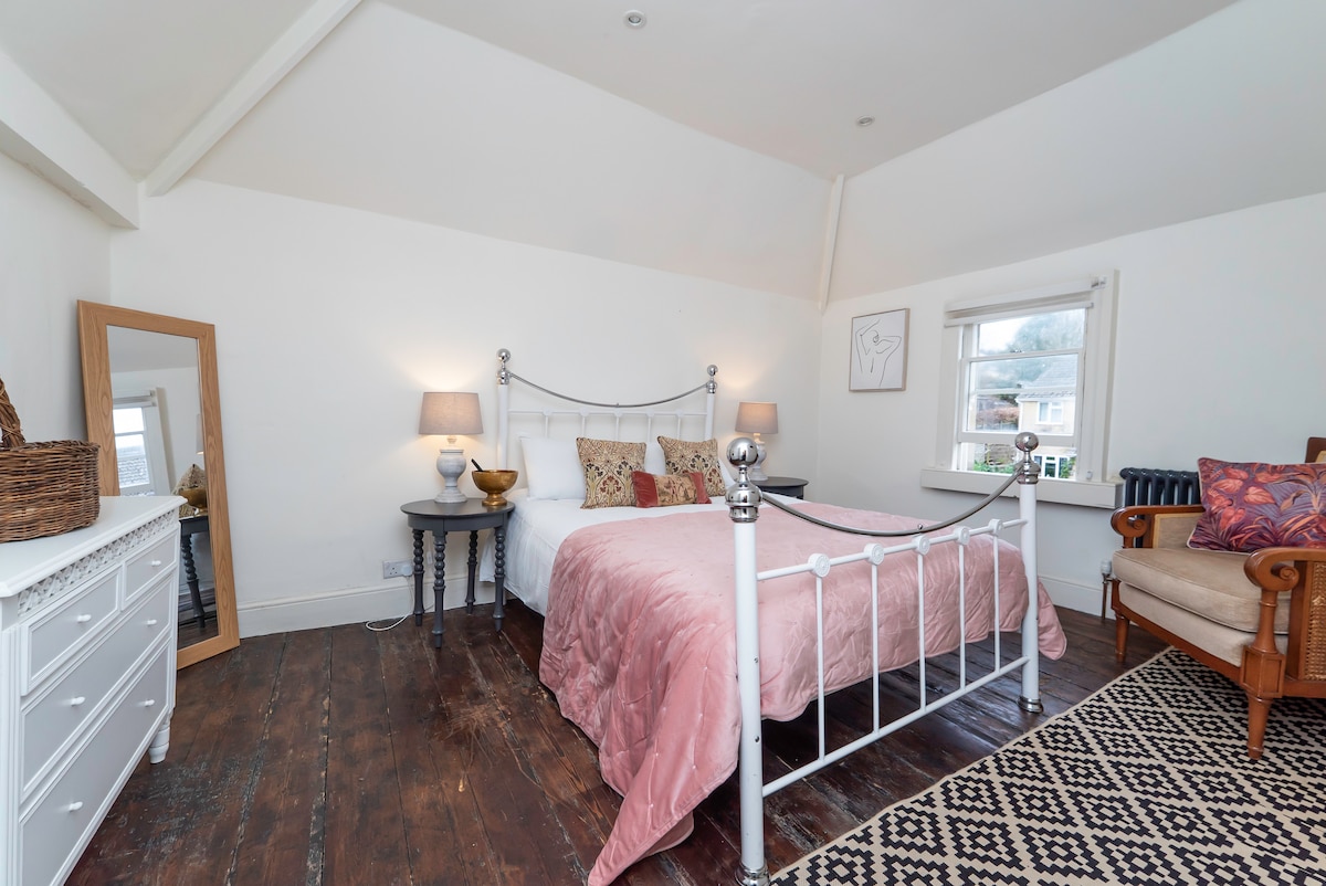 Bedroom with a white iron bed and a pink velvet throw