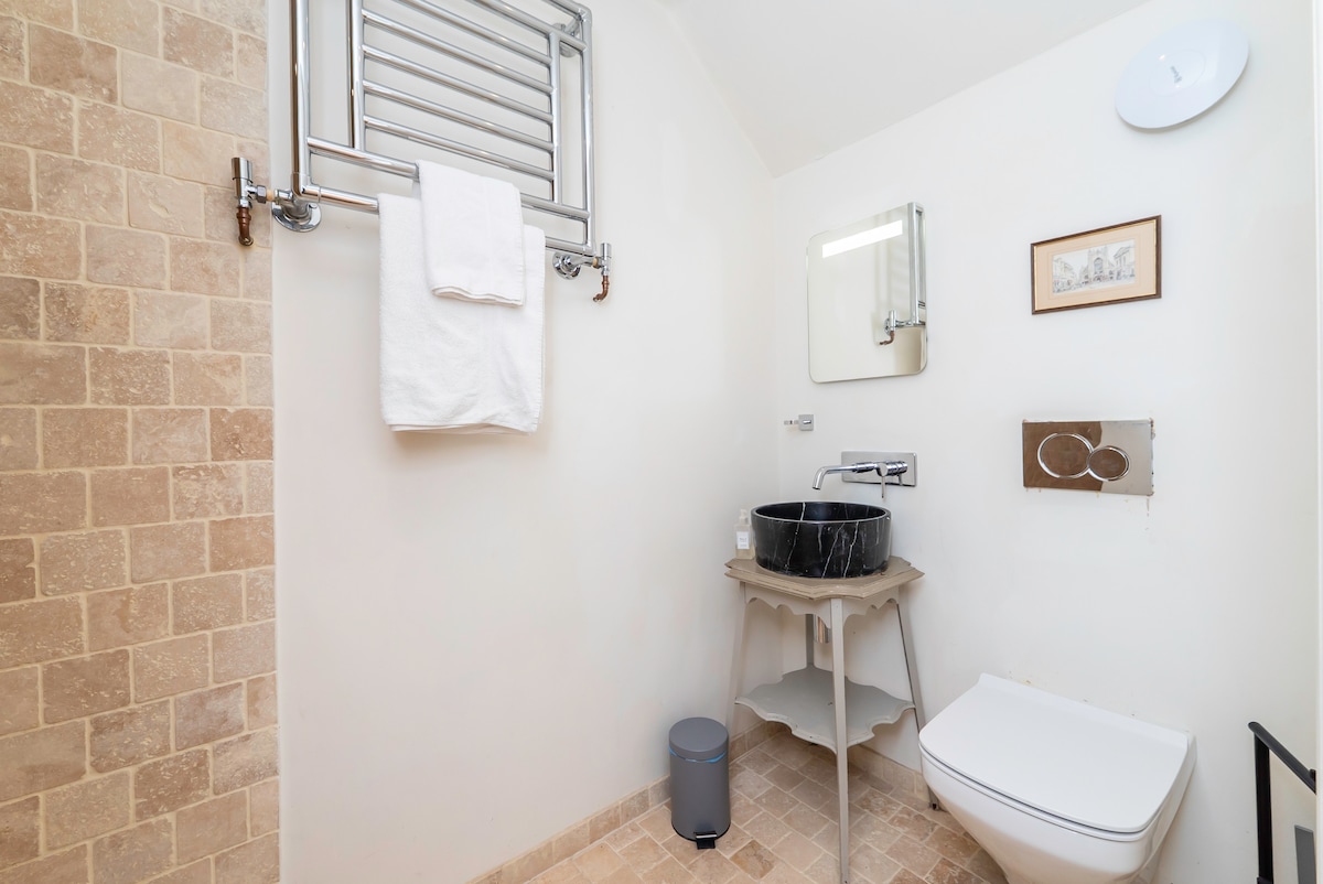 Travertine tiled walk-in wet room with basin and heated towel rail