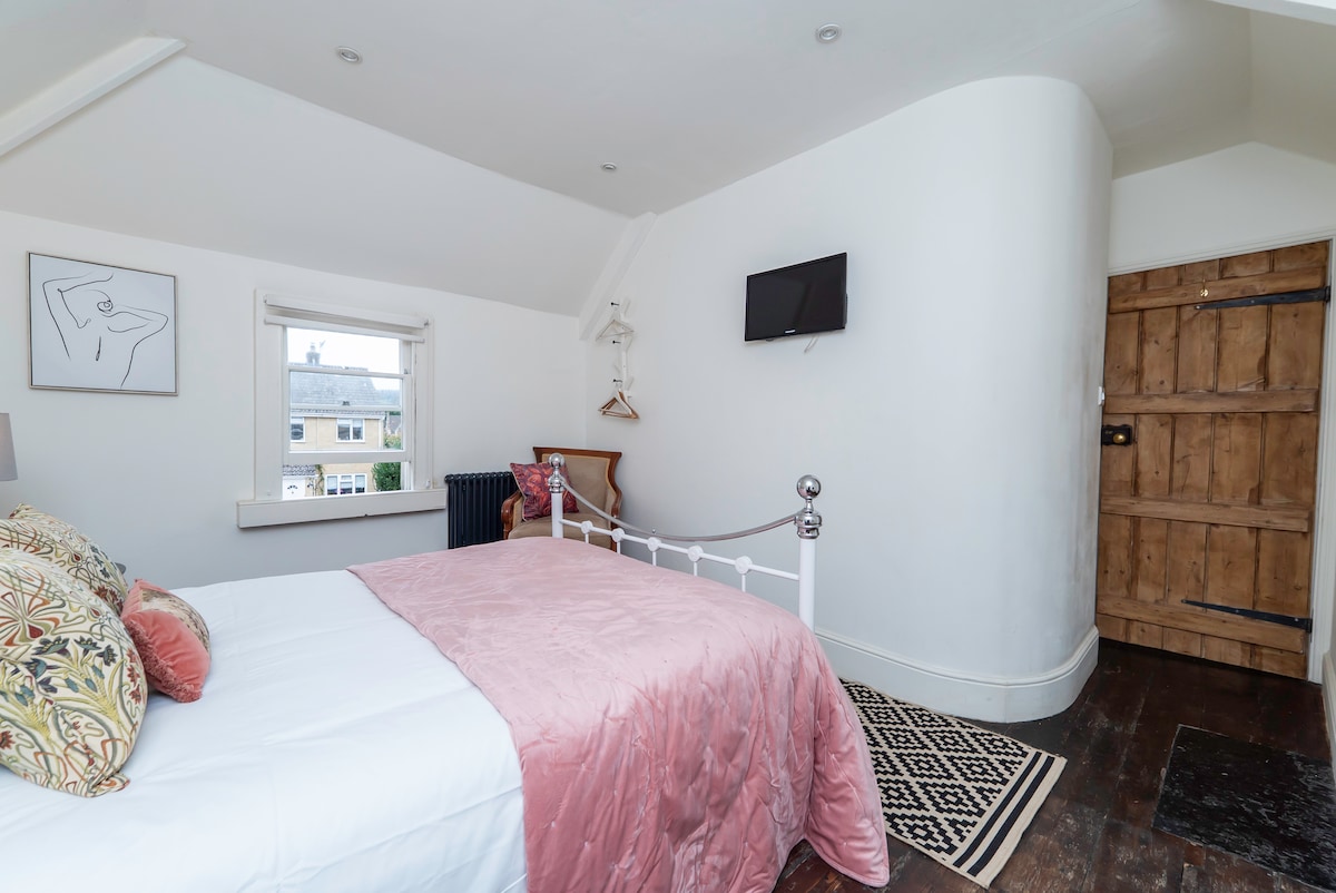 Bedroom with a pink throw, curved wall and an original plank door