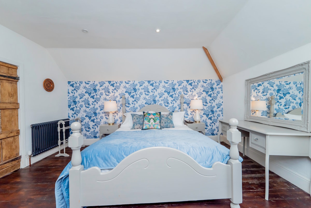 Blue bedroom with dressing table, mirror and floral feature wall