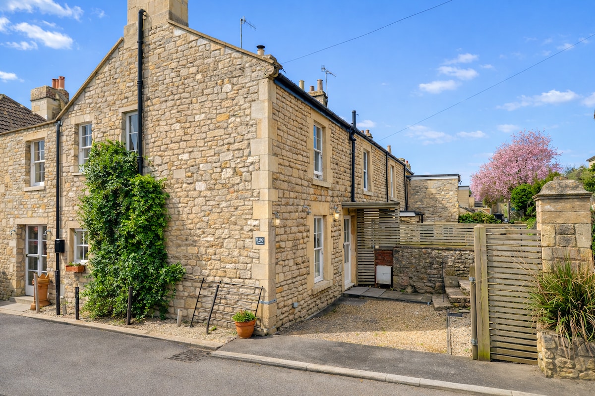Bath stone cottage exterior with climbing greenery and blossom