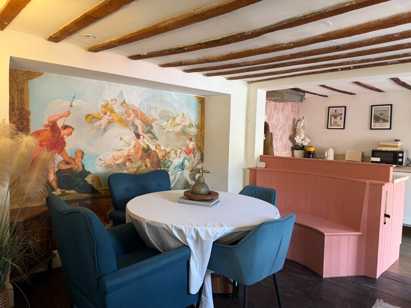 Period dining room with mural, round table and pink banquette
