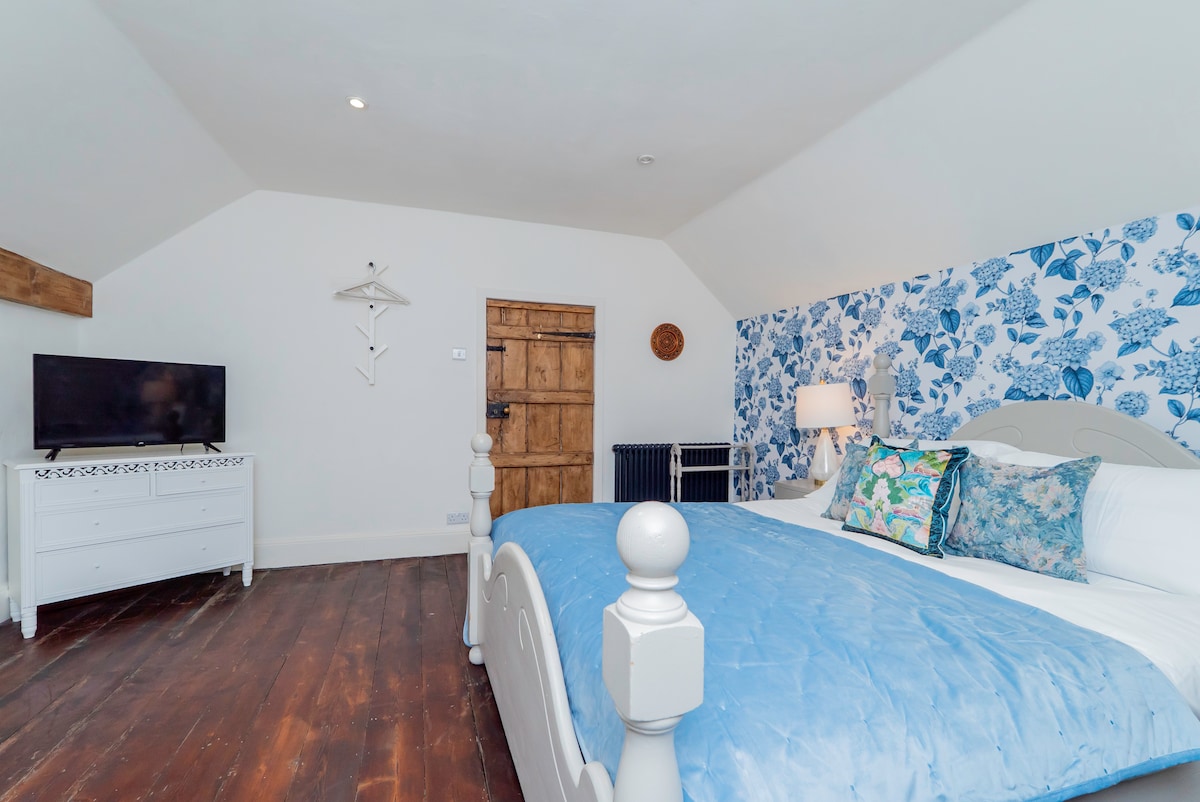 Bedroom with blue hydrangea wallpaper and a painted wooden bed